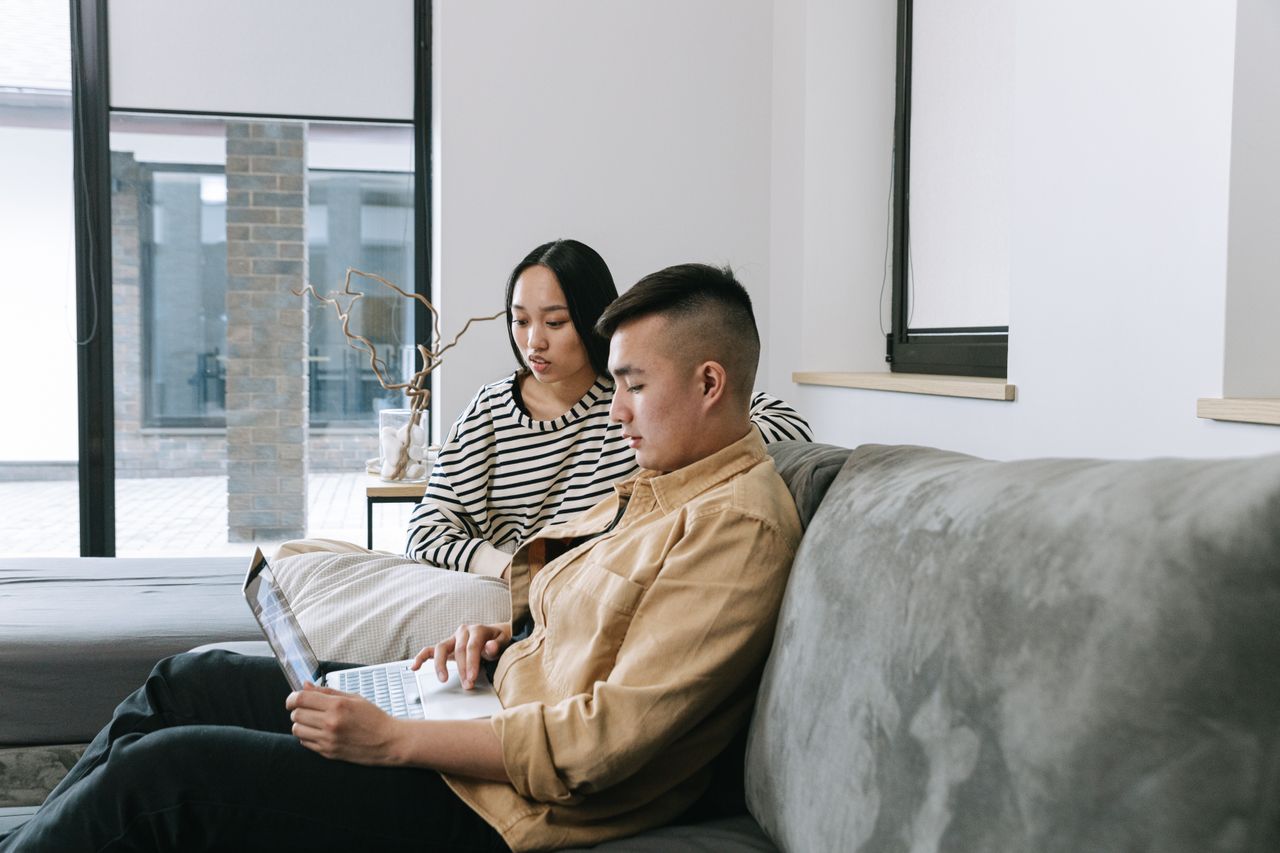 Dos adultos trabajando desde casa con un portátil