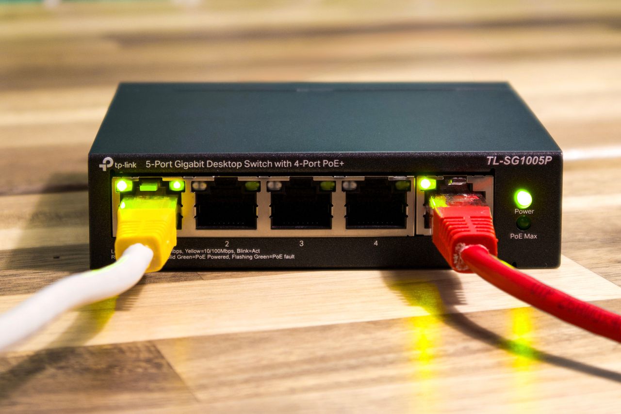 Switch Ethernet con cables conectados sobre una superficie de madera